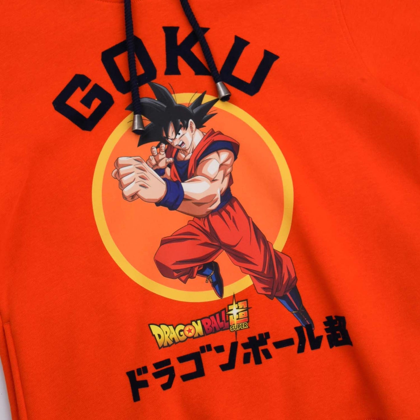 Polerón naranja de Dragon Ball con ilustración de Goku en pose de combate, fondo circular amarillo, texto en japonés y logotipo, ideal para fans.