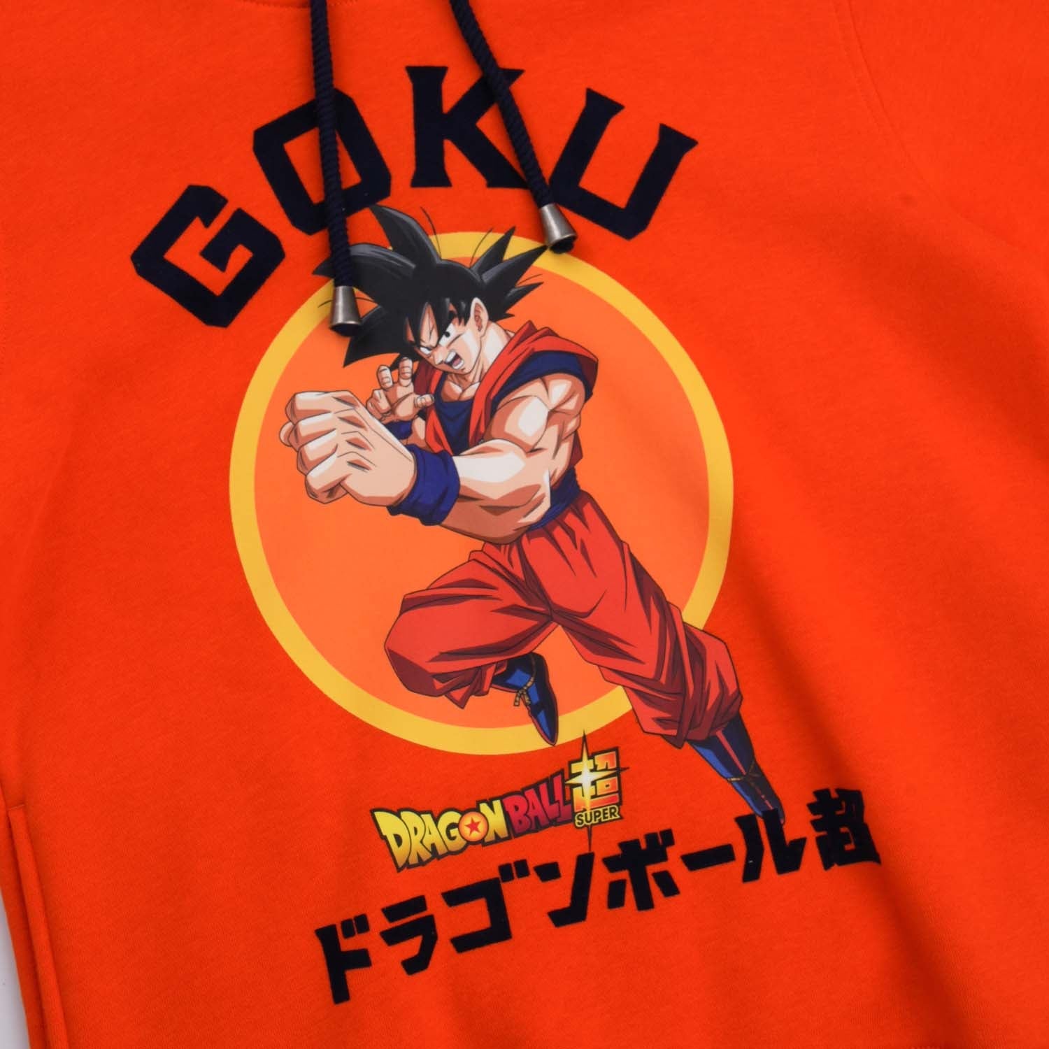 Polerón naranja de Dragon Ball con ilustración de Goku en pose de combate, fondo circular amarillo, texto en japonés y logotipo, ideal para fans.