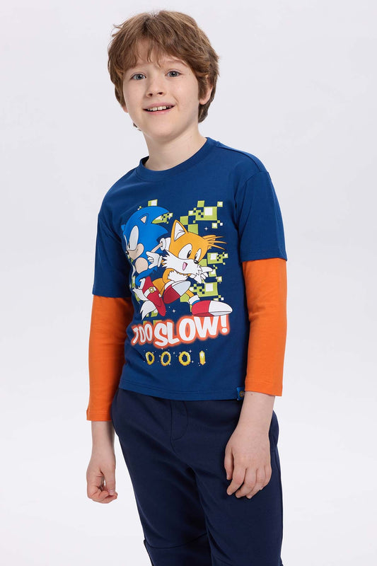 Polera azul con estampado de Sonic y Tails en estilo cartoon, con fondo pixelado y texto 'TOO SLOW!', ideal para fans de Sega.