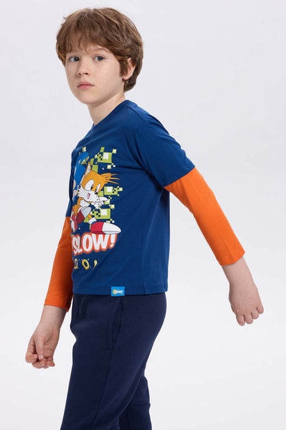 Polera azul con estampado de Sonic y Tails en estilo cartoon, con fondo pixelado y texto 'TOO SLOW!', ideal para fans de Sega.