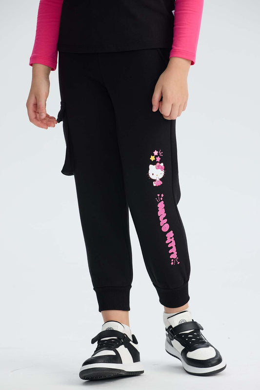 Pantalón buzo cargo negro con estampado de Hello Kitty en tonos rosa y amarillo, mostrando a la icónica gatita con su moño, ideal para fans de Sanrio.