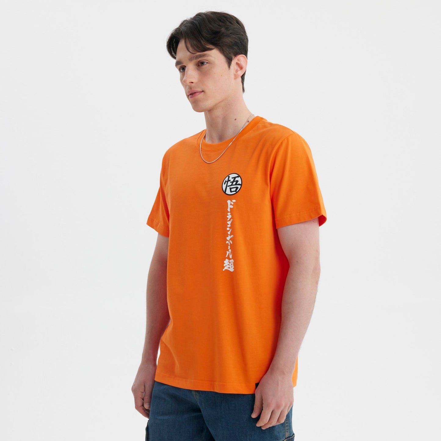 Polera naranja de Dragon Ball con el símbolo de Goku en el pecho y caracteres japoneses en vertical, ideal para fans del anime.