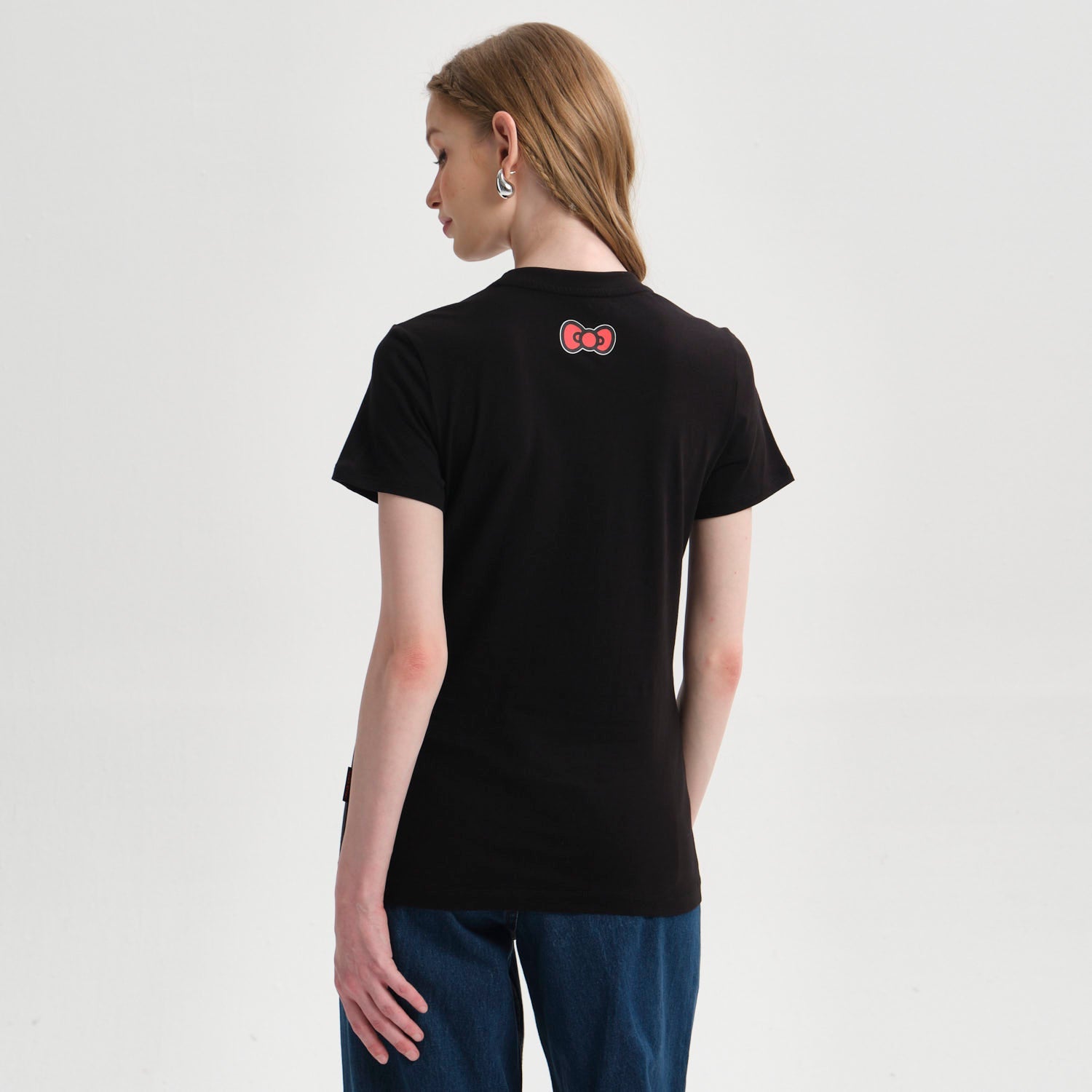 Polera negra de algodón con estampado vibrante de Hello Kitty y sus amigos, mostrando personajes icónicos en una divertida reunión, ideal para fans del universo Sanrio.