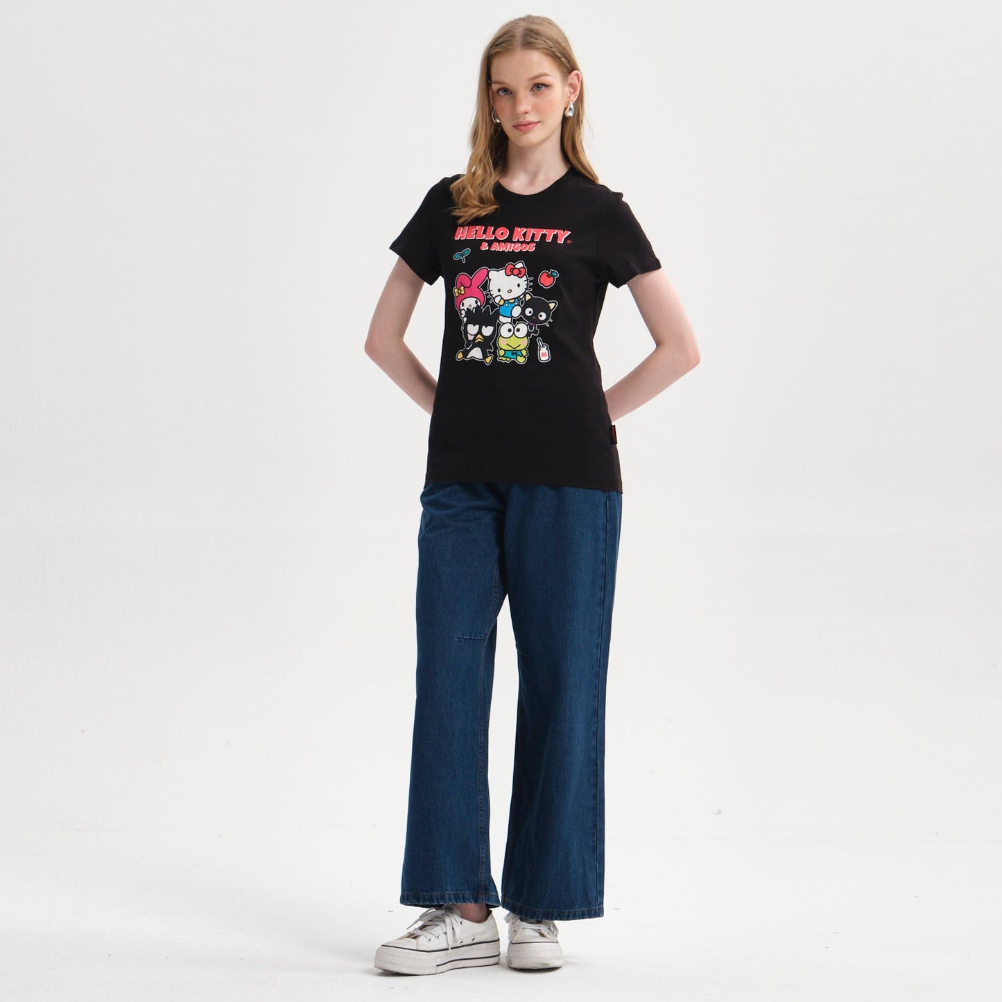 Polera negra de algodón con estampado vibrante de Hello Kitty y sus amigos, mostrando personajes icónicos en una divertida reunión, ideal para fans del universo Sanrio.
