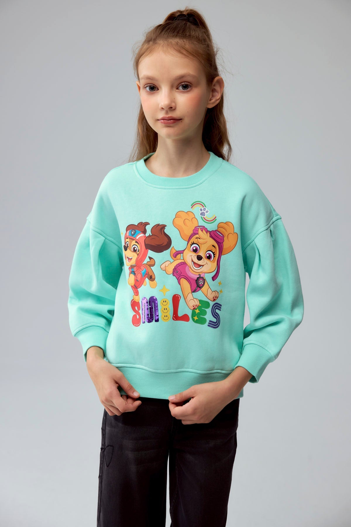 Polerón aqua con ilustración de Skye y Everest de Paw Patrol en acción, con letras coloridas que dicen 'SMILES', ideal para fans de la serie.