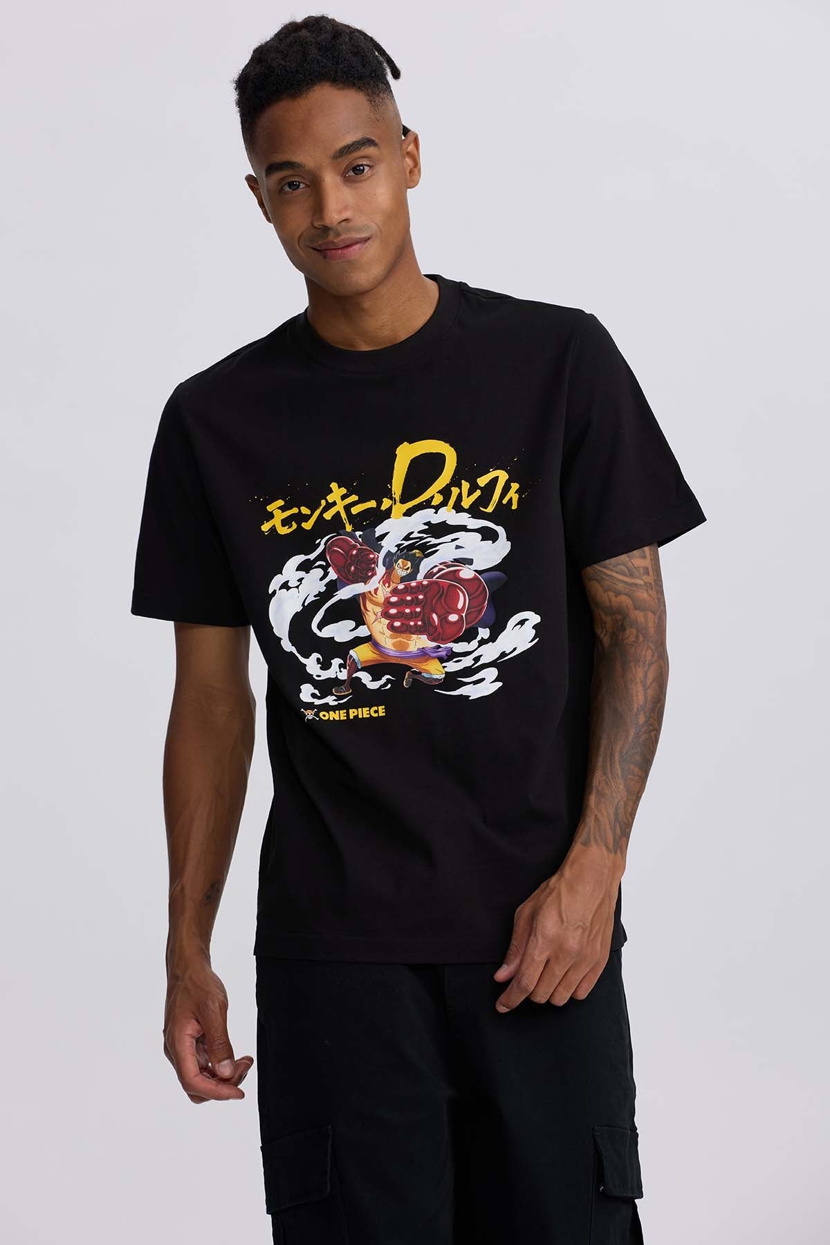Polera negra de algodón con estampado de Luffy en su forma Gear 4, mostrando puños gigantes y nubes de energía, destacando el título 'One Piece'.