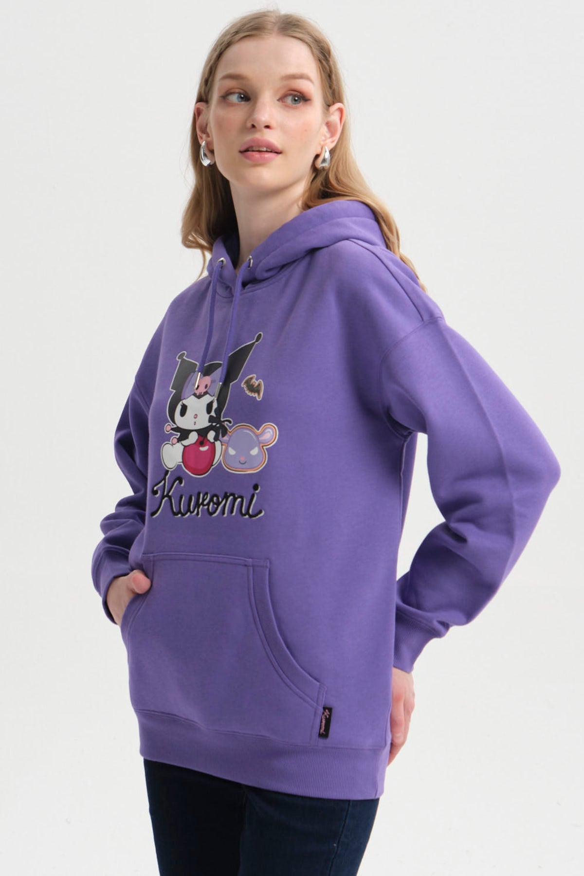 Polerón morado con ilustración de Kuromi sosteniendo una bola roja y acompañada de un personaje gris, diseño vibrante y divertido en el centro.