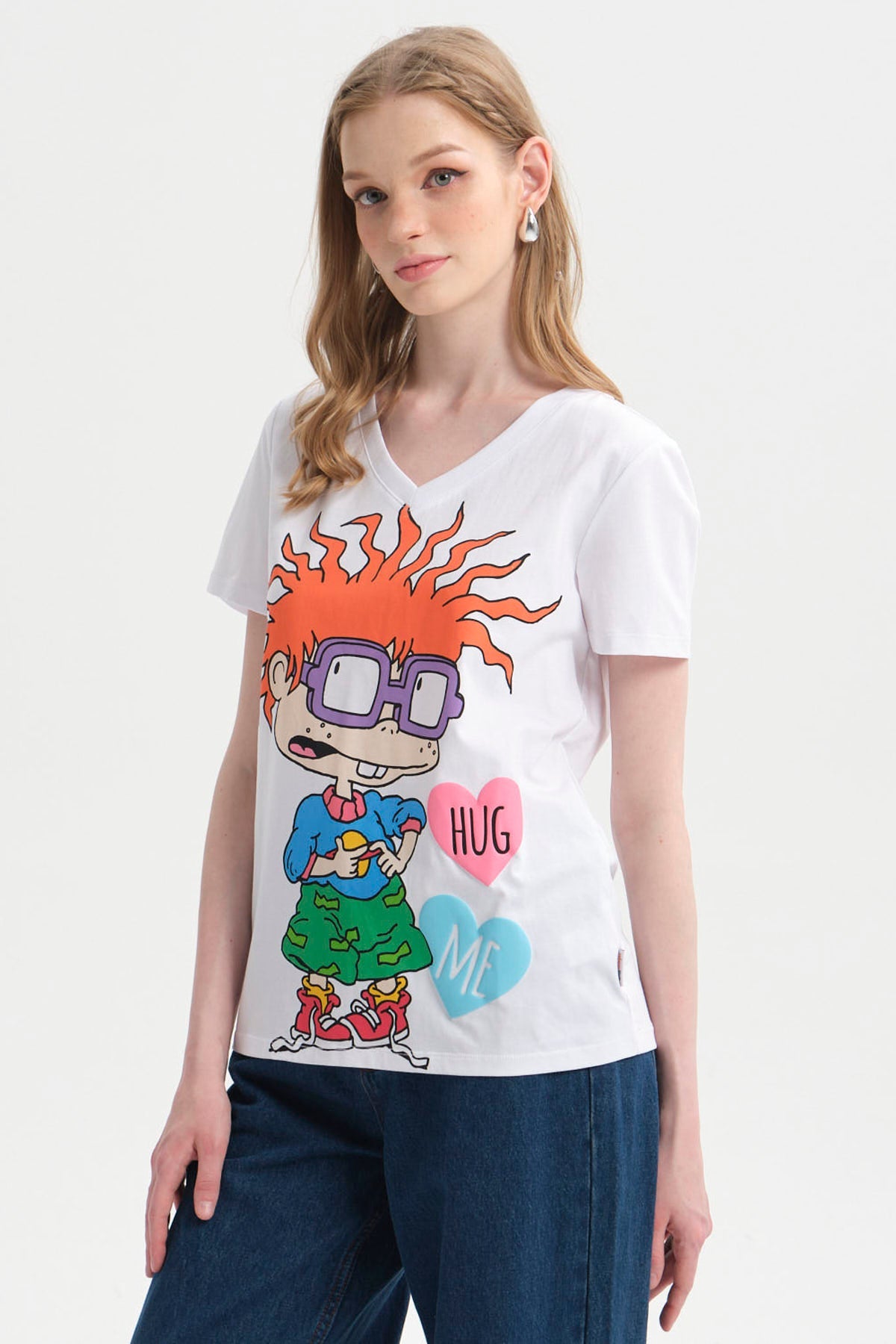 Polera blanca con la ilustración de Carlitos de Rugrats, mostrando su característico cabello rojo y gafas, acompañado de corazones que dicen 'HUG ME'.