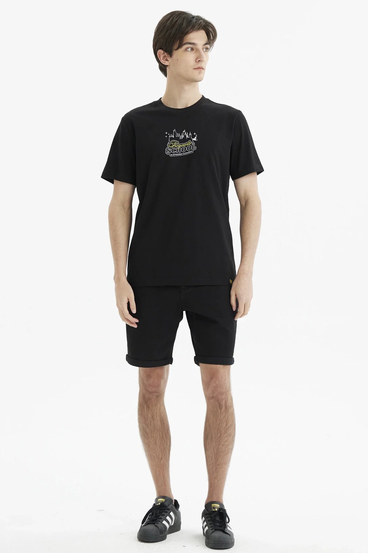 Polera negra de algodón con estampado minimalista de Hogwarts School en el pecho, destacando el castillo y varitas mágicas, ideal para fans de Harry Potter.