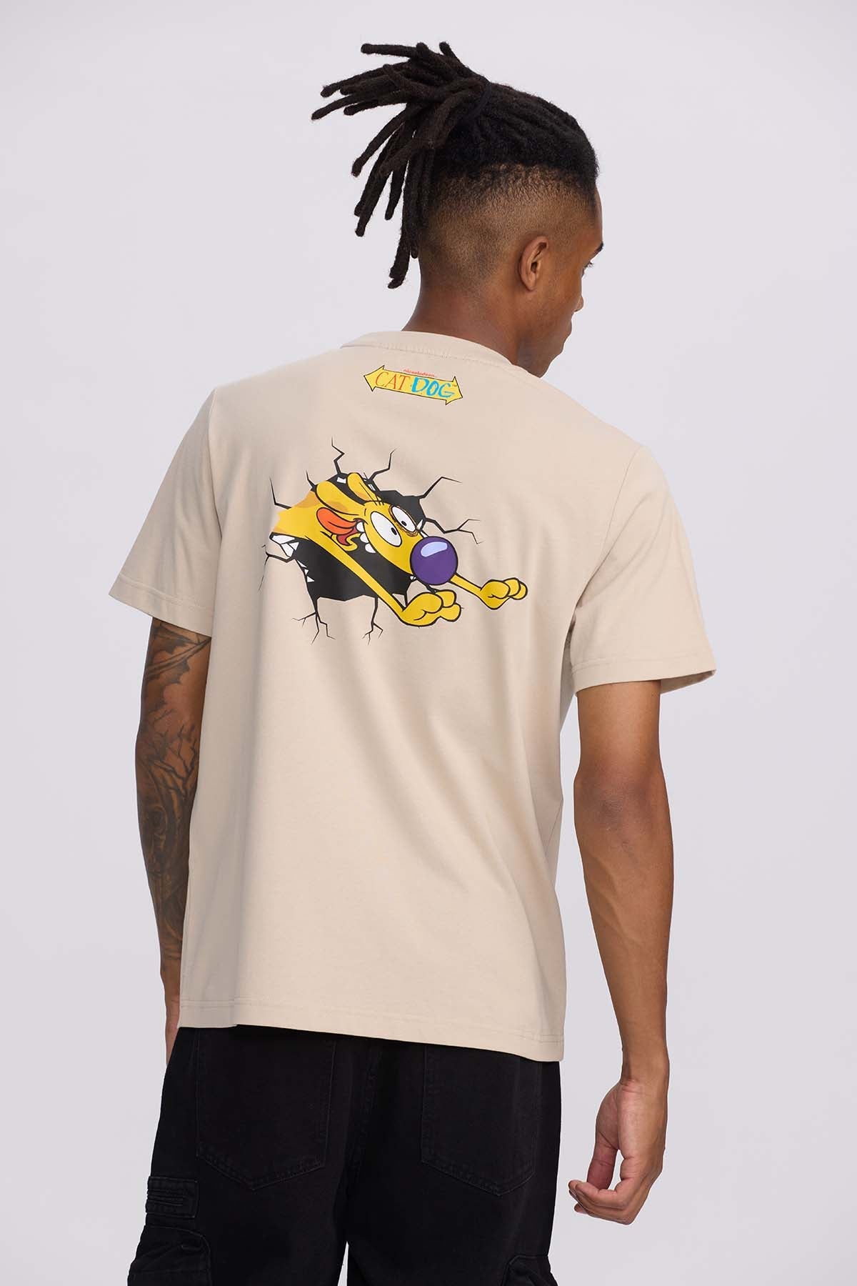Polera beige de algodón con ilustración de CatDog rompiendo la tela, destacando su personalidad única y divertida, ideal para fans de Nickelodeon.