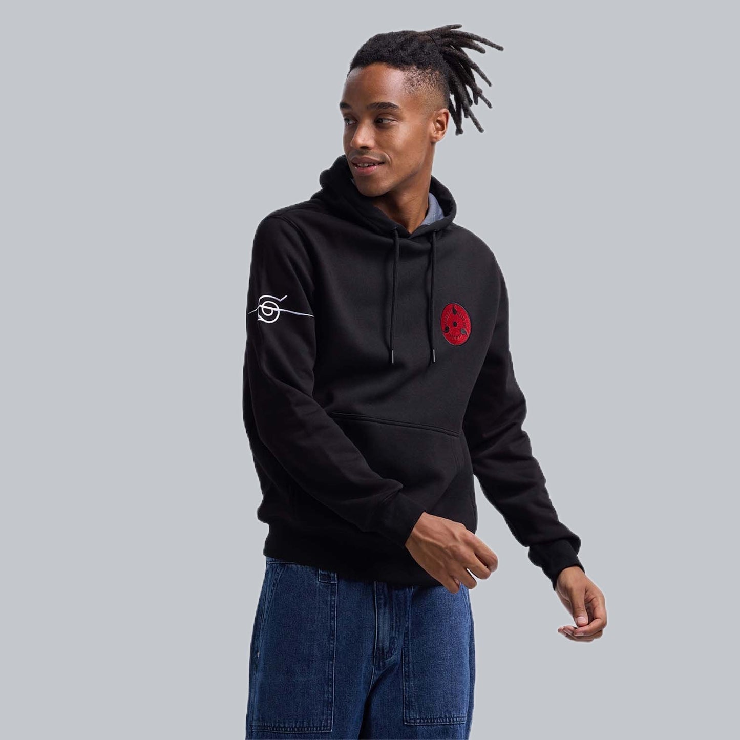Polerón negro de Naruto Shippuden con un distintivo emblema rojo del clan Uchiha en el pecho y logo de la aldea en la manga, ideal para los fans del anime.