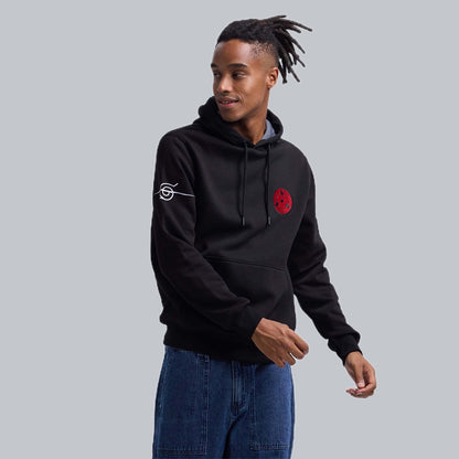 Polerón negro de Naruto Shippuden con un distintivo emblema rojo del clan Uchiha en el pecho y logo de la aldea en la manga, ideal para los fans del anime.