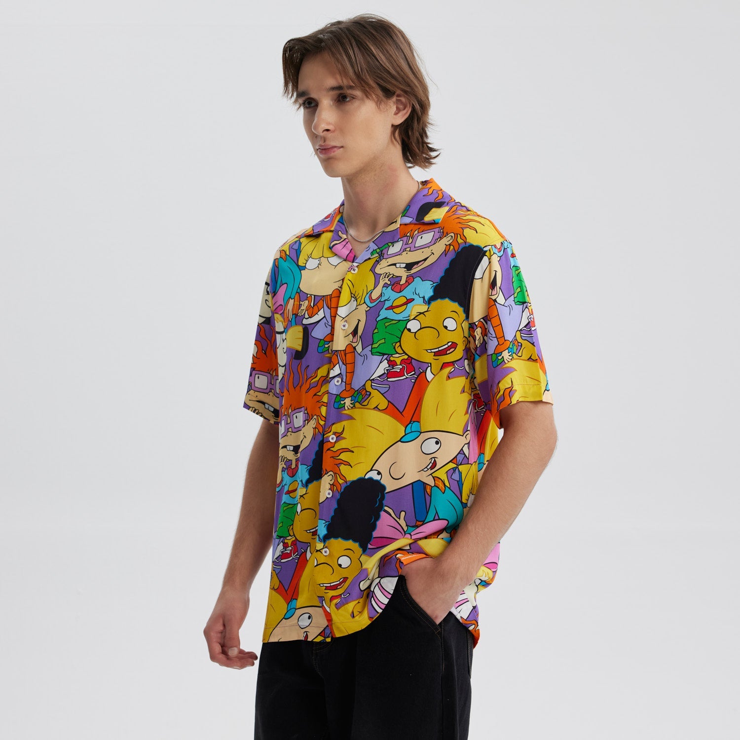 Camisa de manga corta lila con estampado vibrante de personajes icónicos de Nickelodeon como Arnold y Helga, en un diseño alegre y colorido que evoca la nostalgia de los 90.