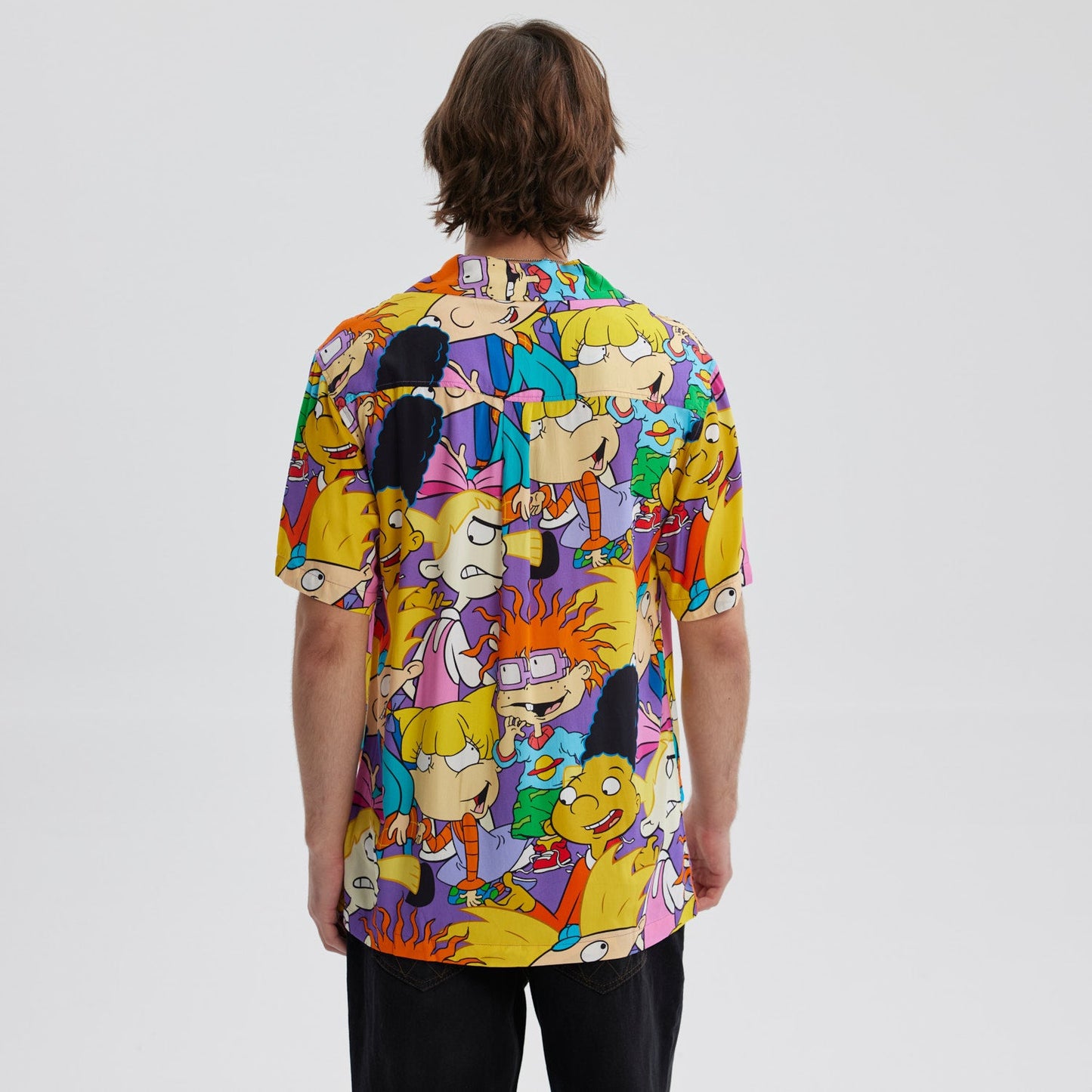 Camisa de manga corta lila con estampado vibrante de personajes icónicos de Nickelodeon como Arnold y Helga, en un diseño alegre y colorido que evoca la nostalgia de los 90.