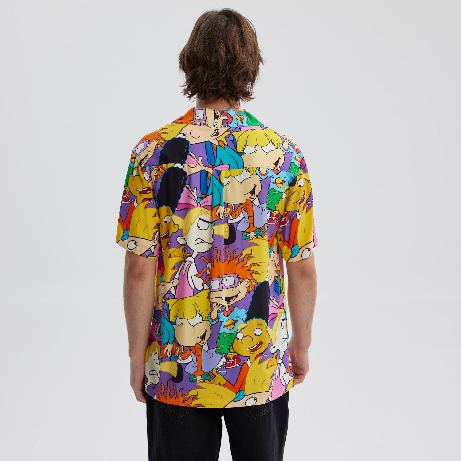 Camisa de manga corta lila con estampado vibrante de personajes icónicos de Nickelodeon como Arnold y Helga, en un diseño alegre y colorido que evoca la nostalgia de los 90.