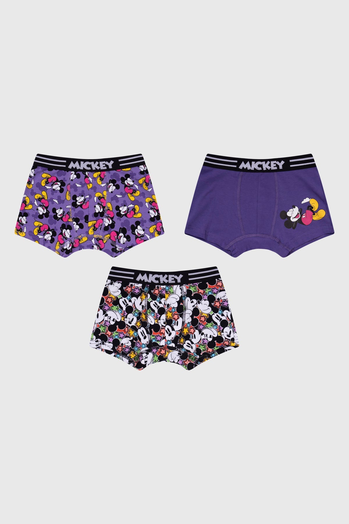 Bóxer tripack en tonos morados y negros con estampados vibrantes de Mickey Mouse en diversas poses, ideal para fans de Disney.