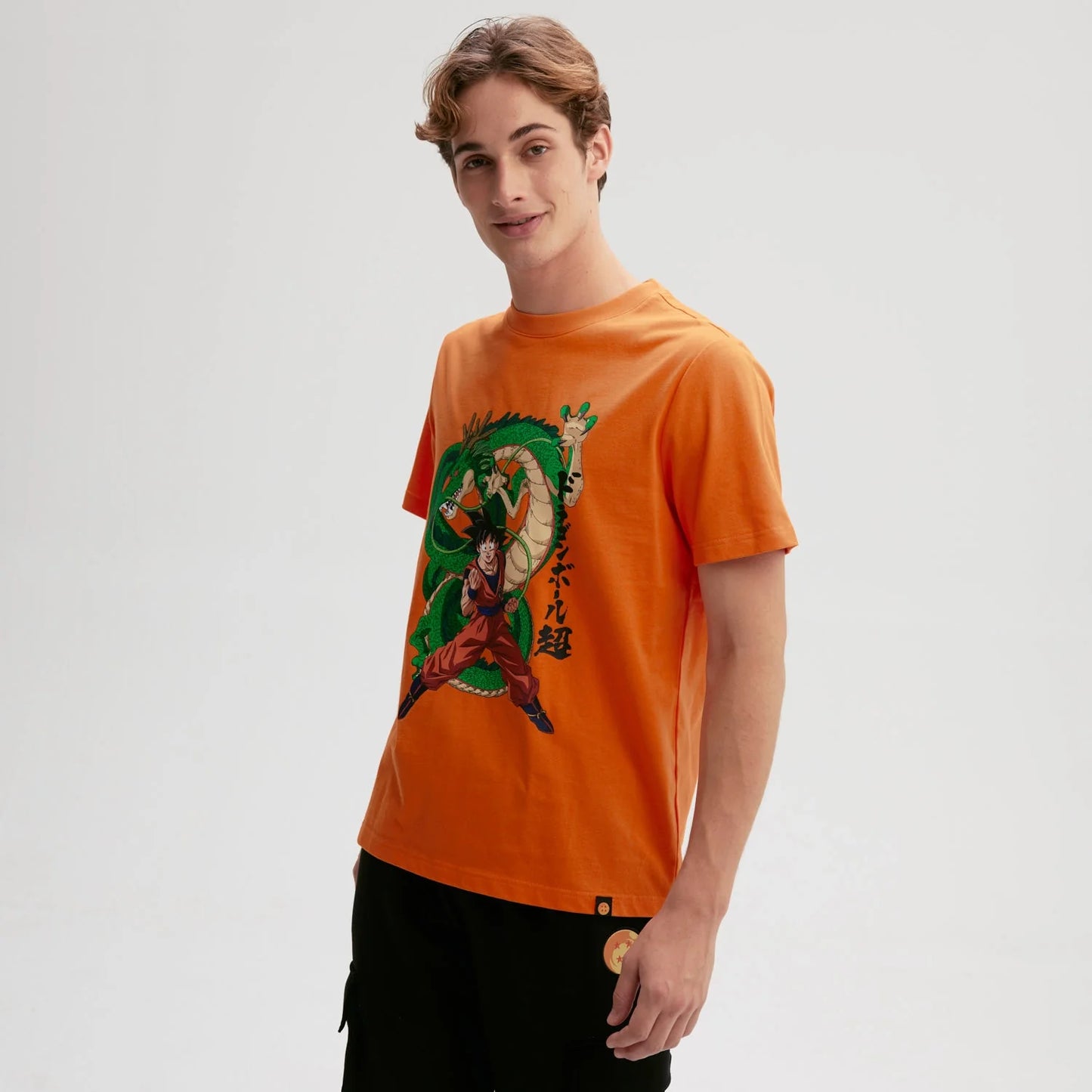 Polera naranjo de Dragon Ball con Goku en pose de combate y Shenlong detrás, ilustración vibrante que evoca la esencia del anime clásico.