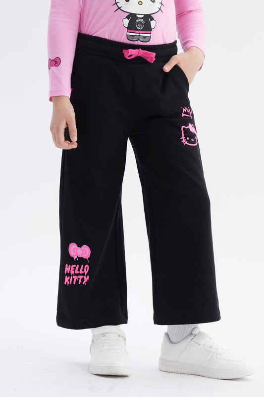 Pantalón buzo negro con detalles en rosa, presenta ilustraciones de Hello Kitty en estilo moderno, ideal para fans de la cultura pop y el kawaii.