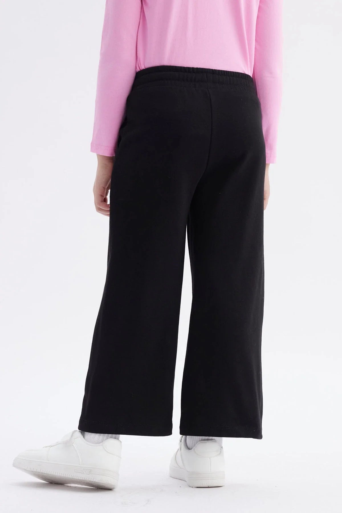 Pantalón buzo negro con detalles en rosa, presenta ilustraciones de Hello Kitty en estilo moderno, ideal para fans de la cultura pop y el kawaii.