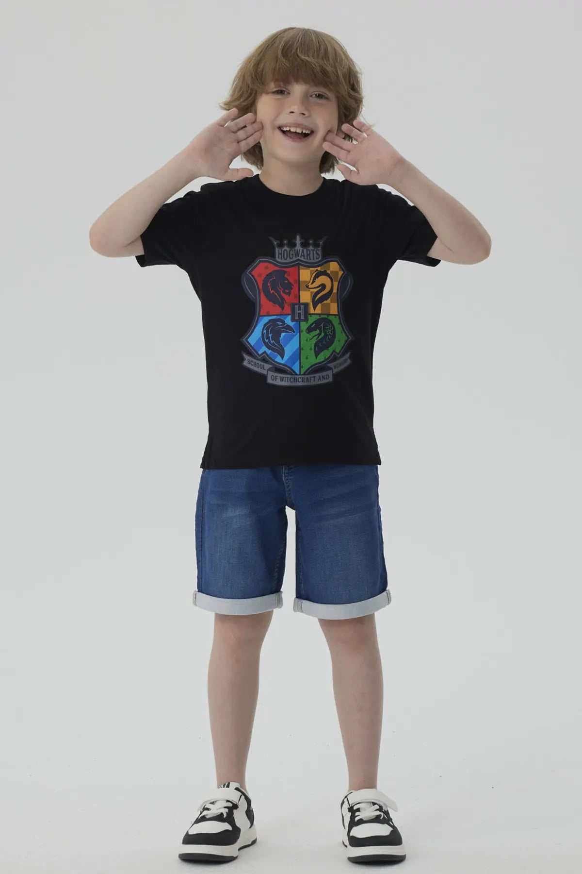 Polera negra de algodón con el escudo de Hogwarts en colores vibrantes representando las casas Gryffindor, Slytherin, Hufflepuff y Ravenclaw, ideal para fans de Harry Potter.