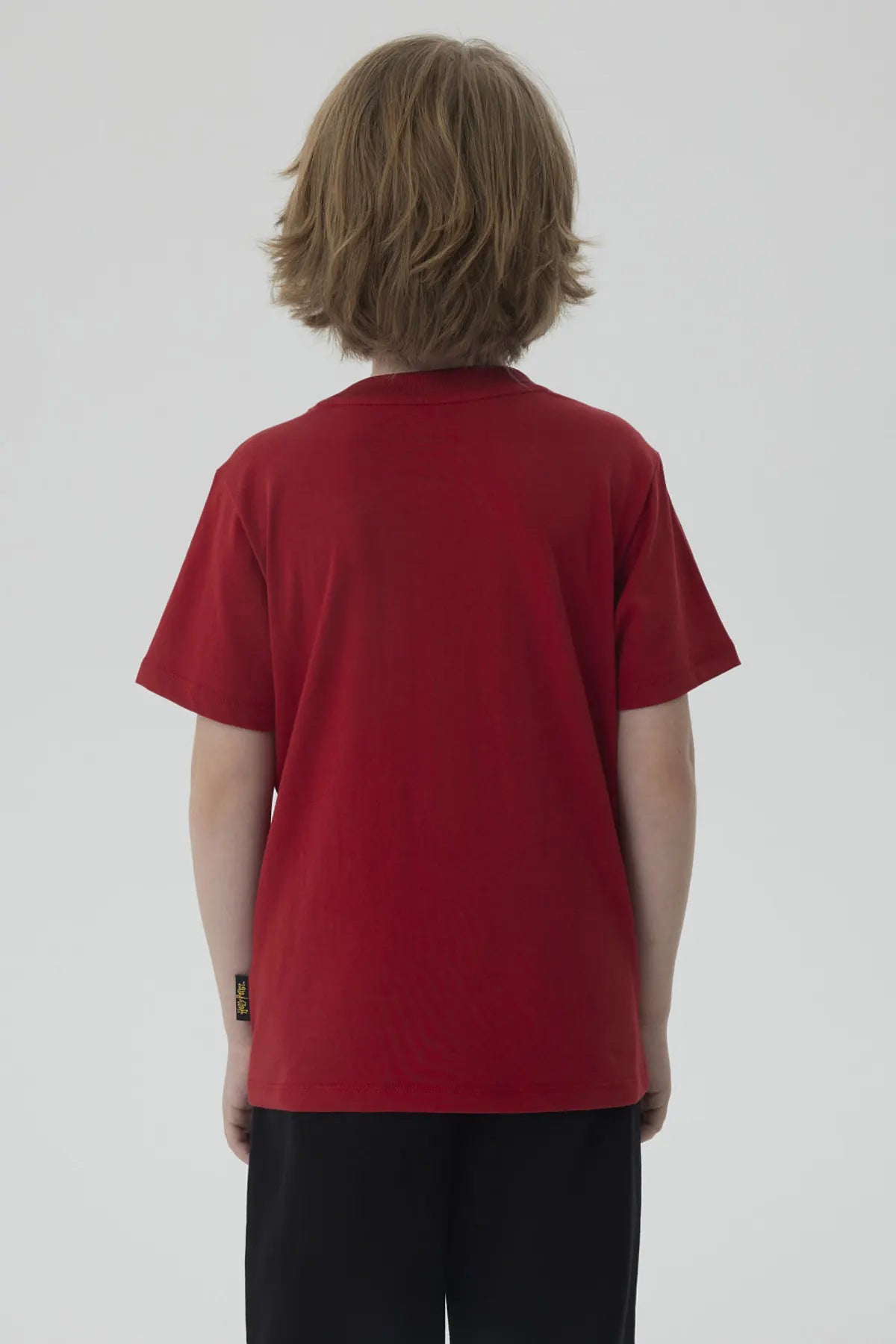 Polera burdeos de algodón con el escudo de Hogwarts en dorado, destacando la frase 'WELCOME TO HOGWARTS', ideal para los pequeños magos fans de Harry Potter.
