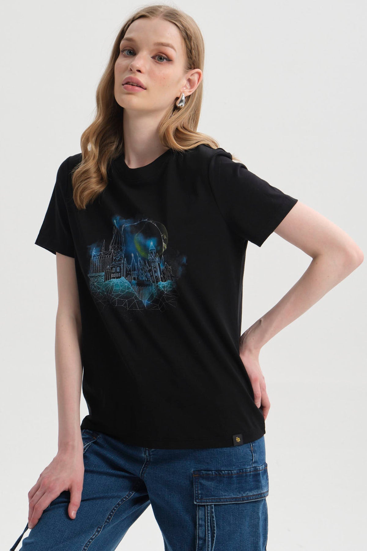 Polera negra de algodón con un estampado vibrante del Castillo Hogwarts en tonos azules y verdes, evocando la magia de Harry Potter.