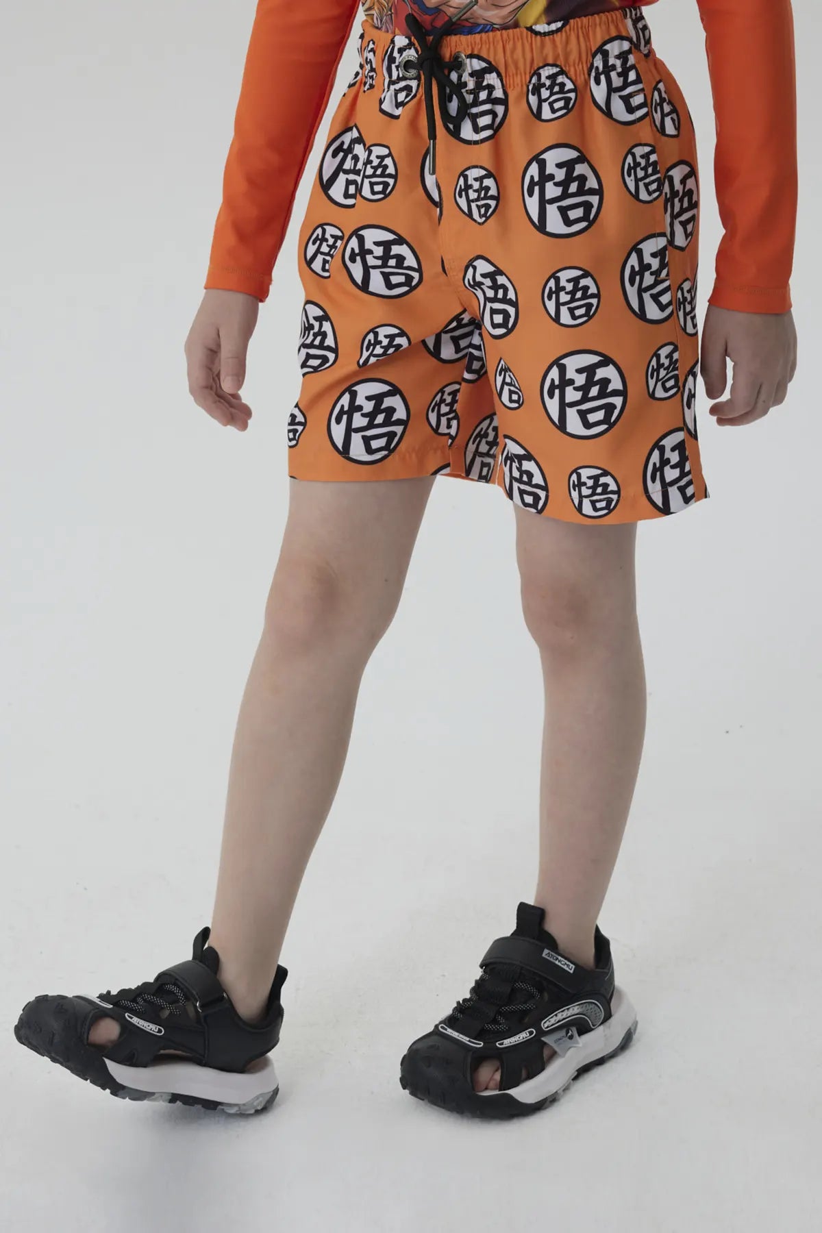 Short de baño naranja con estampado de esferas del dragón en negro, ideal para mostrar tu amor por Dragon Ball mientras disfrutas del verano.