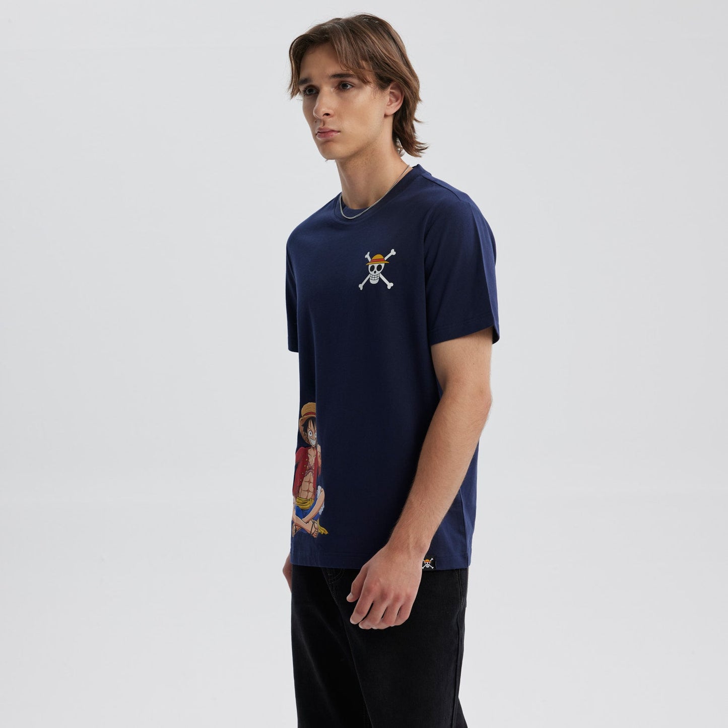Polera azul marino de algodón con ilustración de Luffy en pose relajada y logo de la calavera pirata en el pecho, inspirado en One Piece.