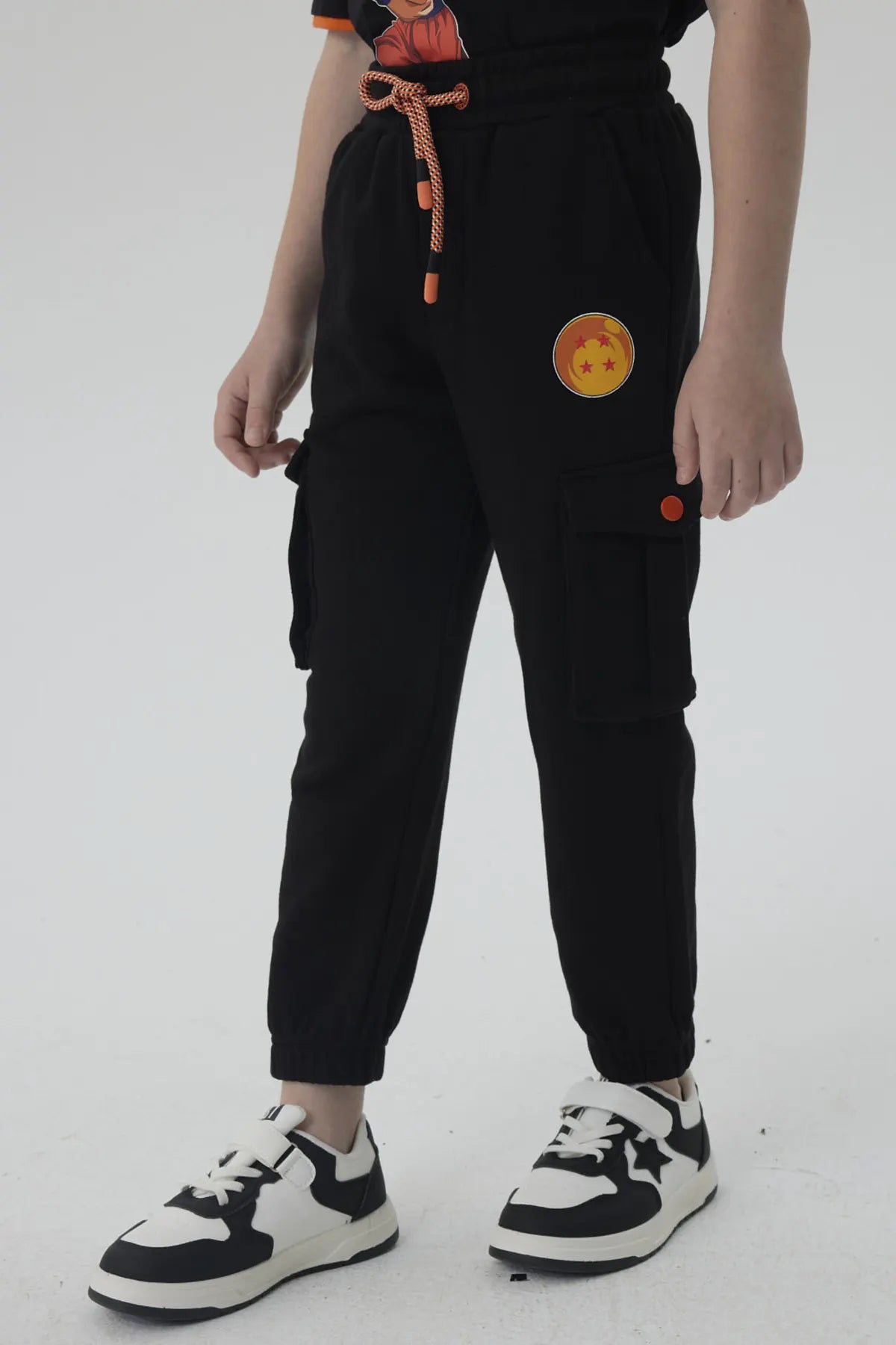 Pantalón buzo negro con detalles en naranja, presenta el icónico logo de Dragon Ball en la pierna, ideal para fans de la saga.