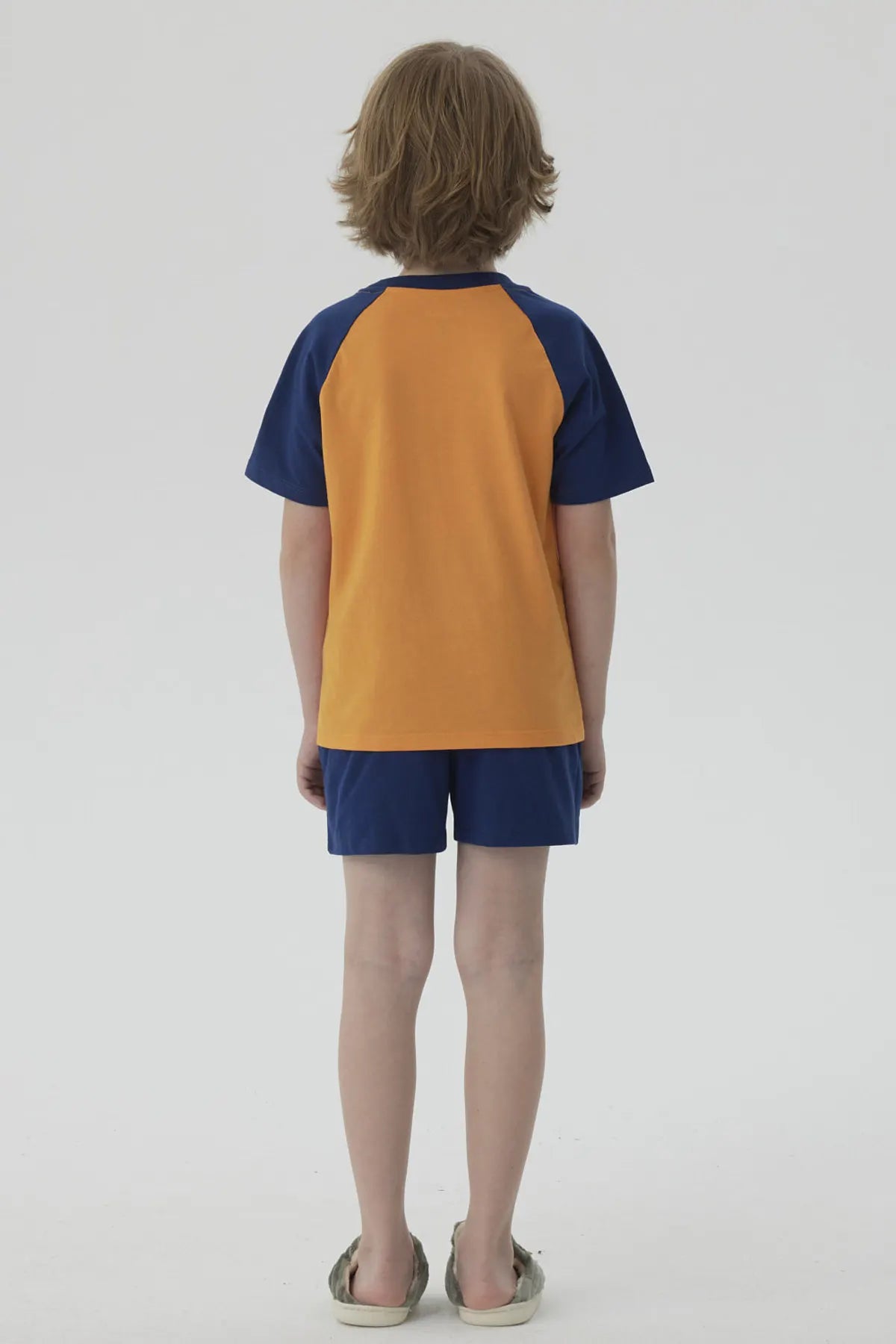 Pijama Dragon Ball azul marino con camiseta naranja que muestra a Goku y Vegeta en acción, con detalles vibrantes y logo en pantalones cortos.
