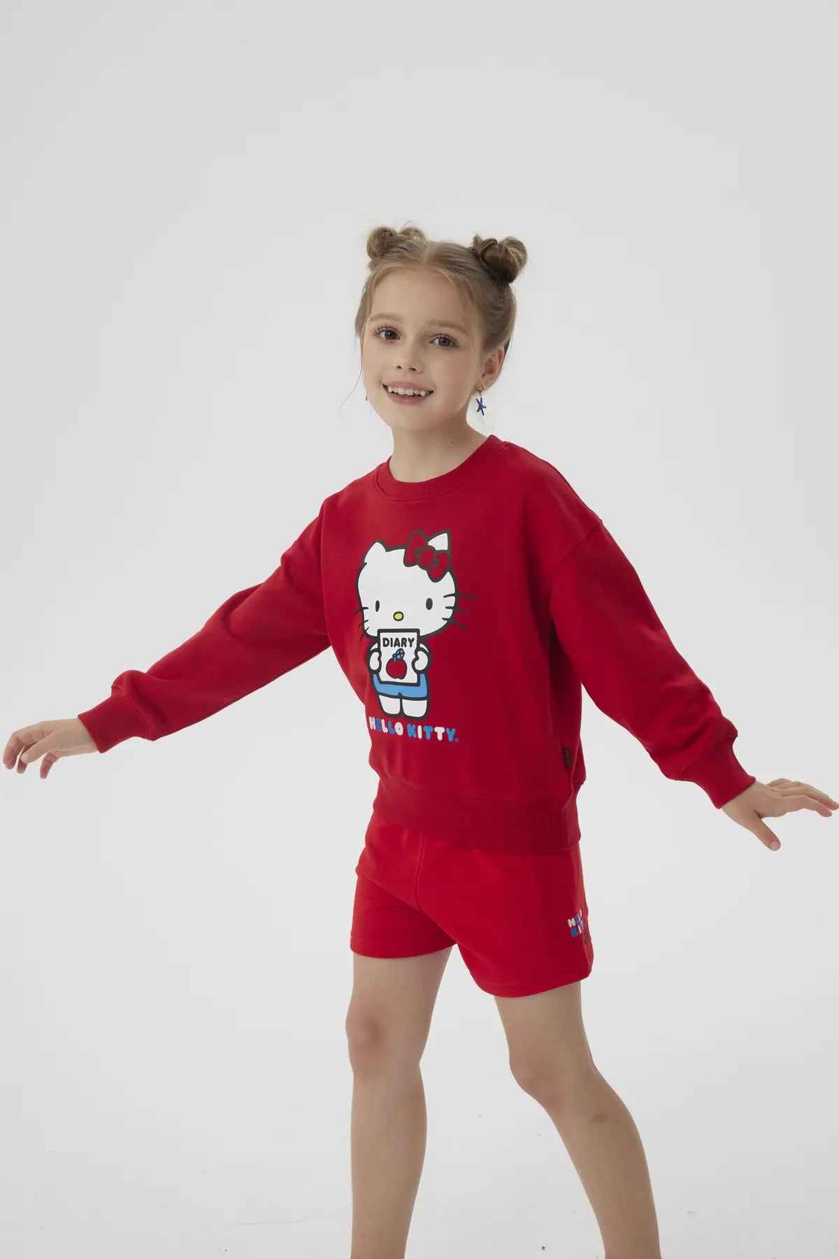 Polerón rojo con ilustración de Hello Kitty sosteniendo un diario, con detalles en azul y el texto 'HELLO KITTY' en la parte inferior, ideal para fans de la icónica gatita.