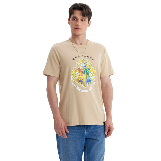 Polera beige de algodón con el escudo de Hogwarts en colores vibrantes, destacando los cuatro emblemas de las casas y la letra H, ideal para fans de Harry Potter.