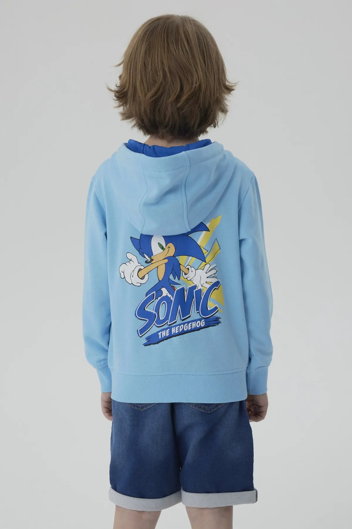 Polerón celeste con capucha, presenta un estampado de Sonic the Hedgehog en un círculo, en el lado izquierdo del pecho, evocando la velocidad y aventura del universo de Sega.