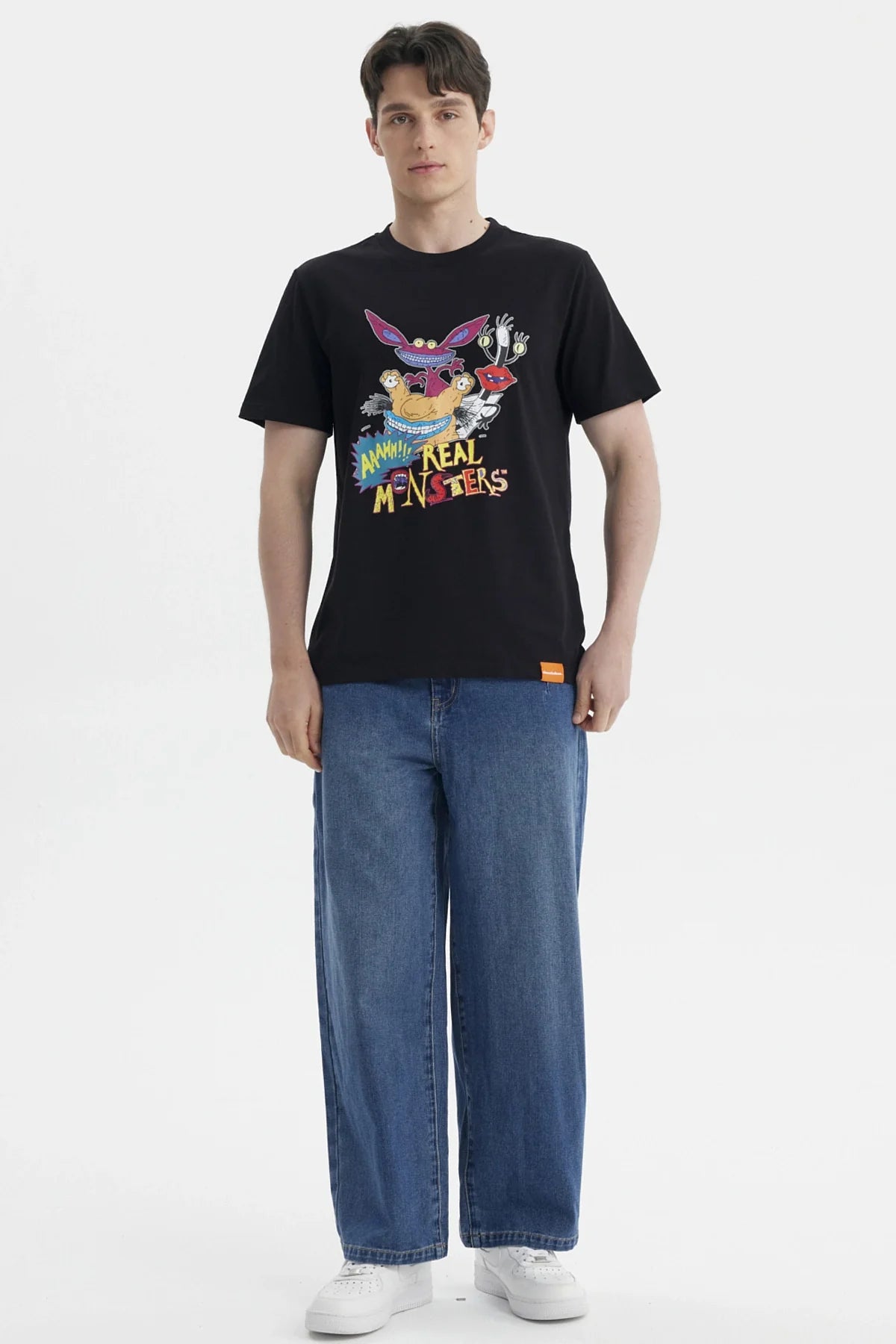 Polera negra de algodón con estampado colorido de personajes de Aaahh!!! Real Monsters, mostrando a Ickis, Oblina y Krumm en acción, ideal para fans nostálgicos.