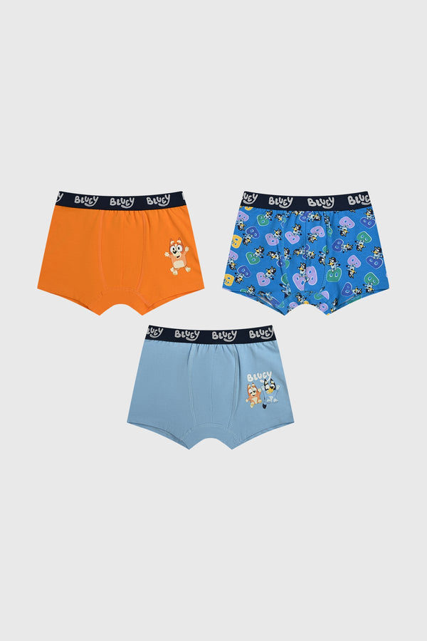 Boxer tripack celeste con estampados de Bluey, uno en naranja con Bluey saltando, otro azul claro con Bluey y Bingo, y un tercero azul marino con múltiples personajes.