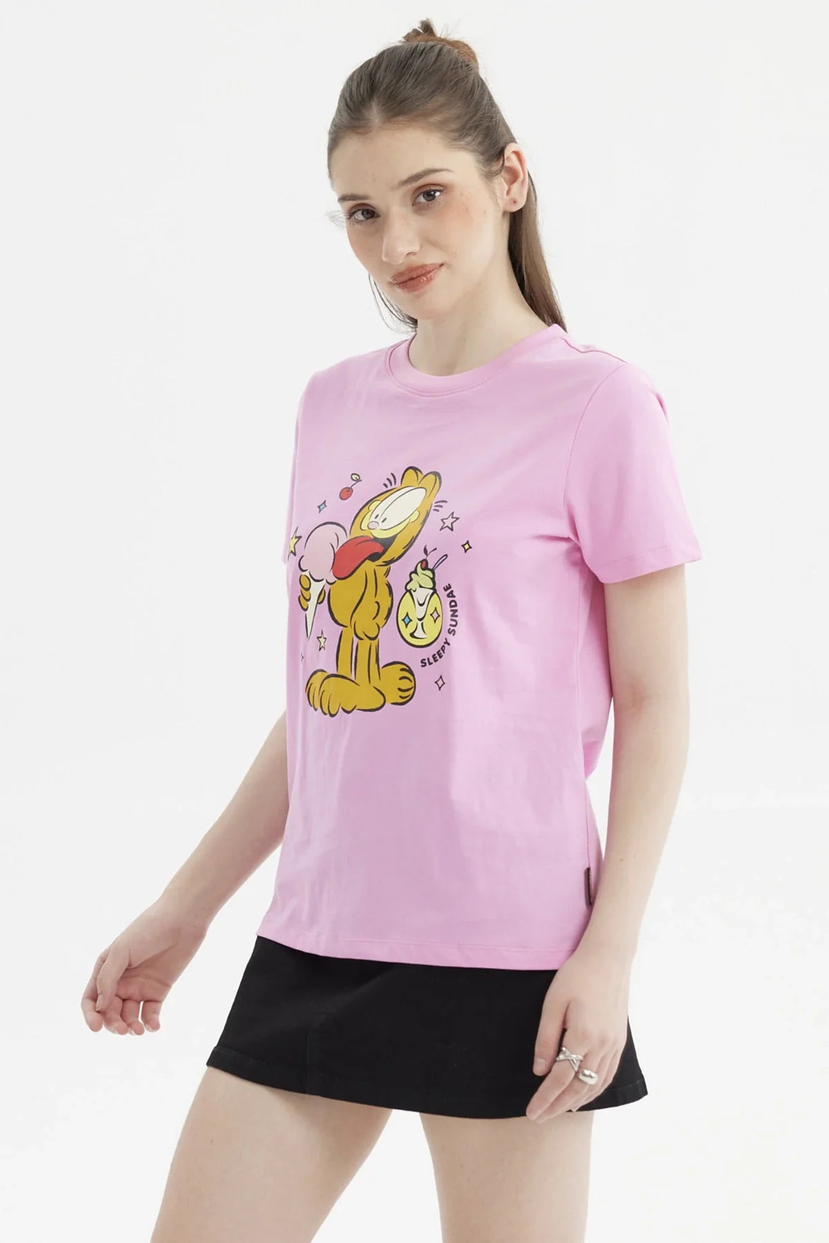Polera rosada de Garfield con ilustración colorida del gato sosteniendo un helado, rodeado de estrellas y cerezas, perfecta para fans del cómic.