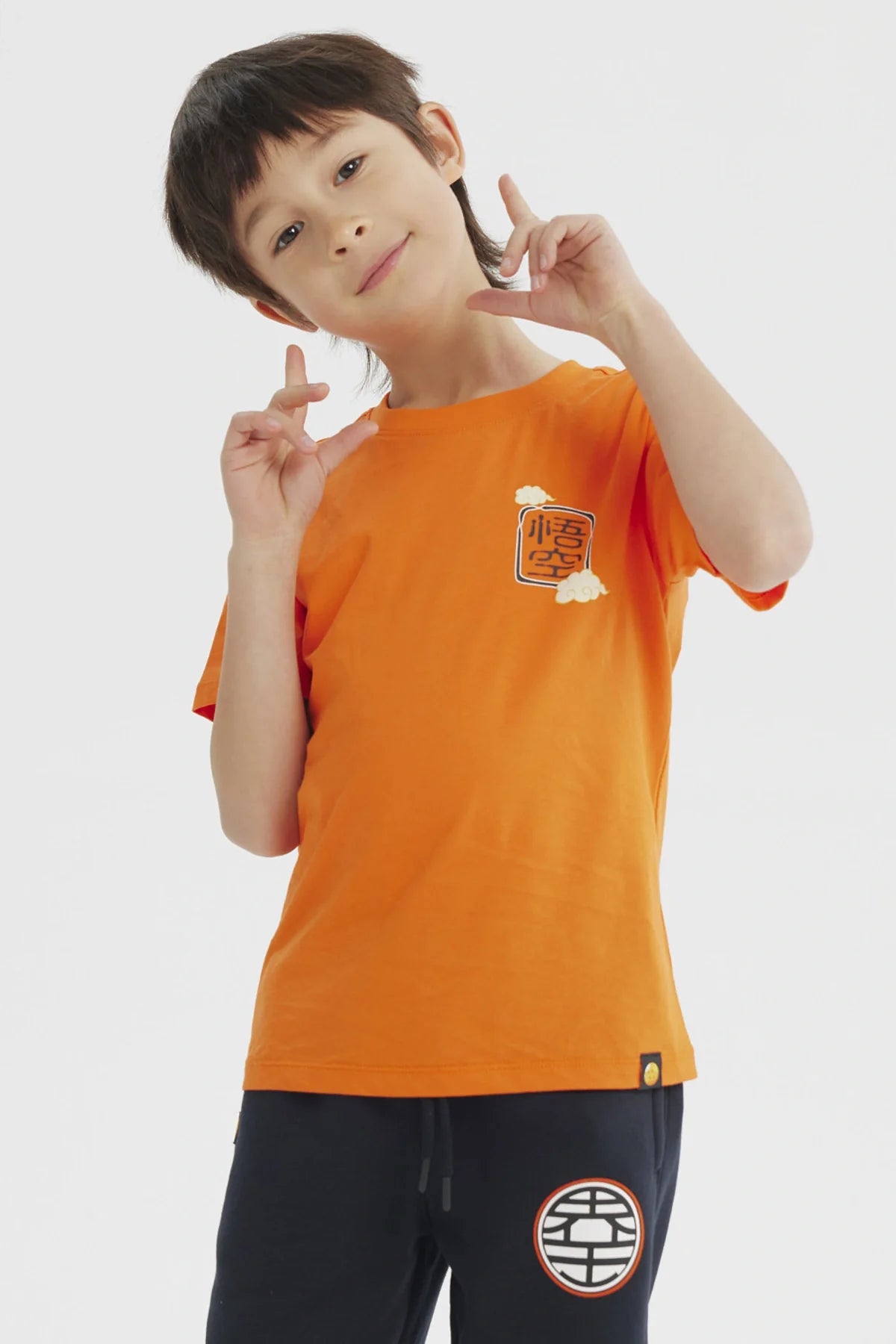 Polera naranja de Dragon Ball Z con estampado frontal de kanji en negro y nubes, ideal para los pequeños guerreros del universo Akira Toriyama.
