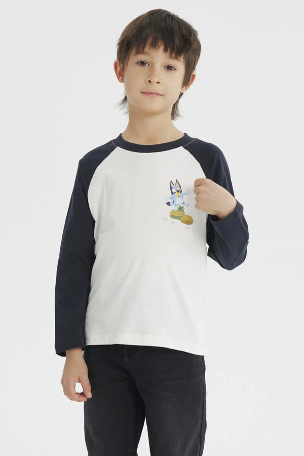 Polera de manga larga azul marino con cuerpo blanco, presenta a Bluey en acción sobre un fondo de colores suaves, ideal para fans de la serie australiana.