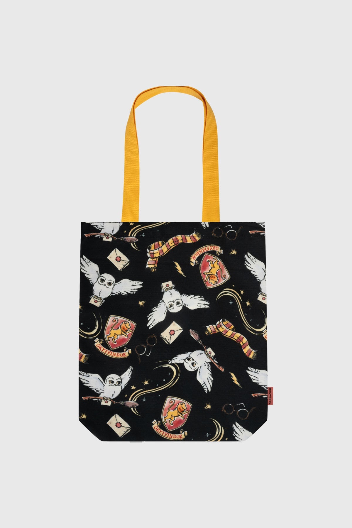 Bolsa negra con estampado de búhos, varitas y escudos de Gryffindor, detalles en amarillo, ideal para fans de Harry Potter.