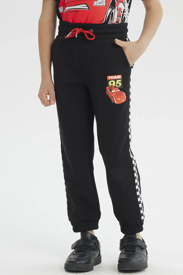 Pantalón buzo negro con detalles de 'Team 95' y un diseño vibrante de Rayo McQueen, ideal para los fans de Cars, con bandas a cuadros en los laterales.