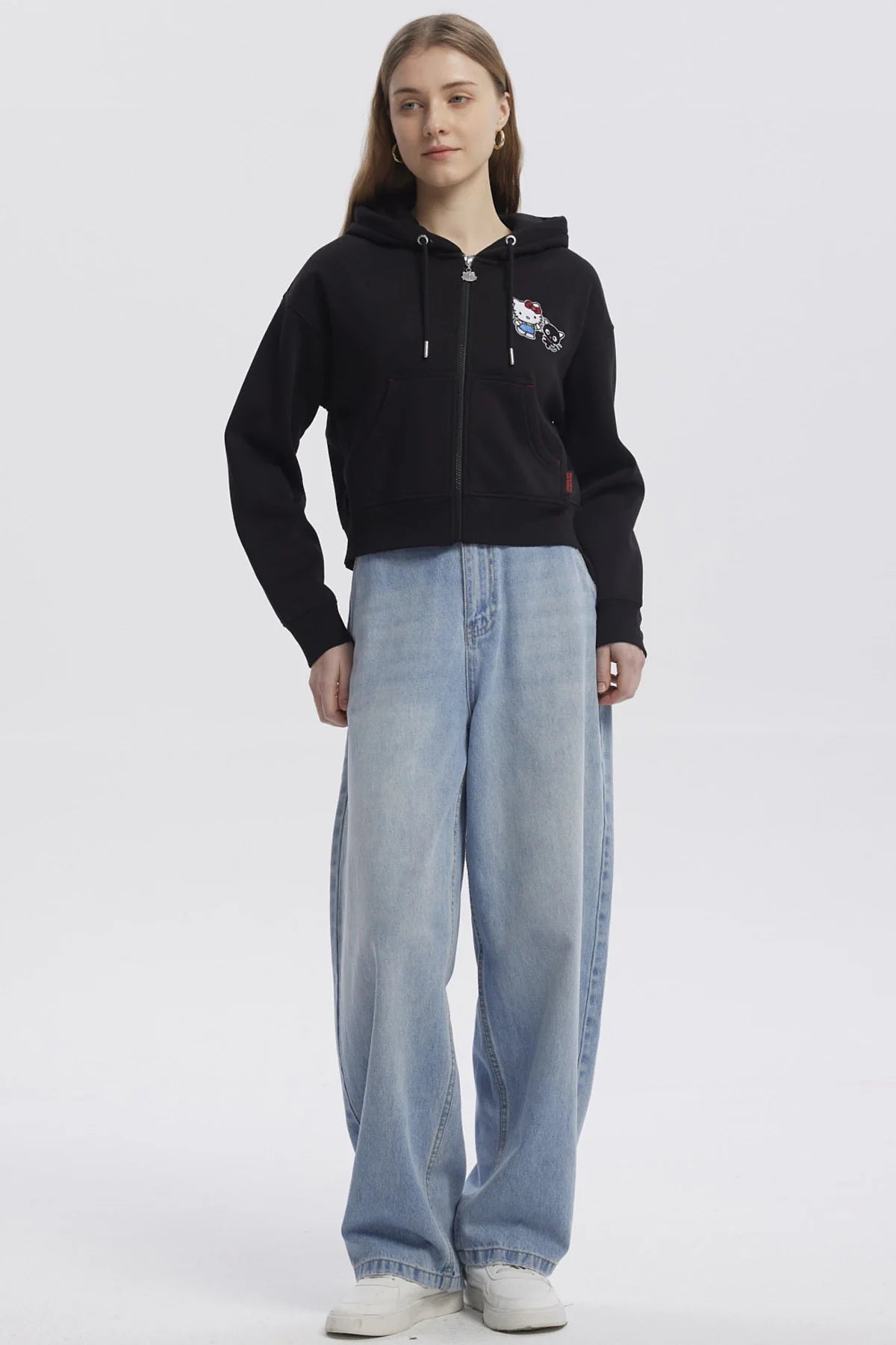 Polerón negro con capucha y cierre, presenta un diseño de Hello Kitty y su amigo negro, ideal para fans de Sanrio que buscan estilo y comodidad.