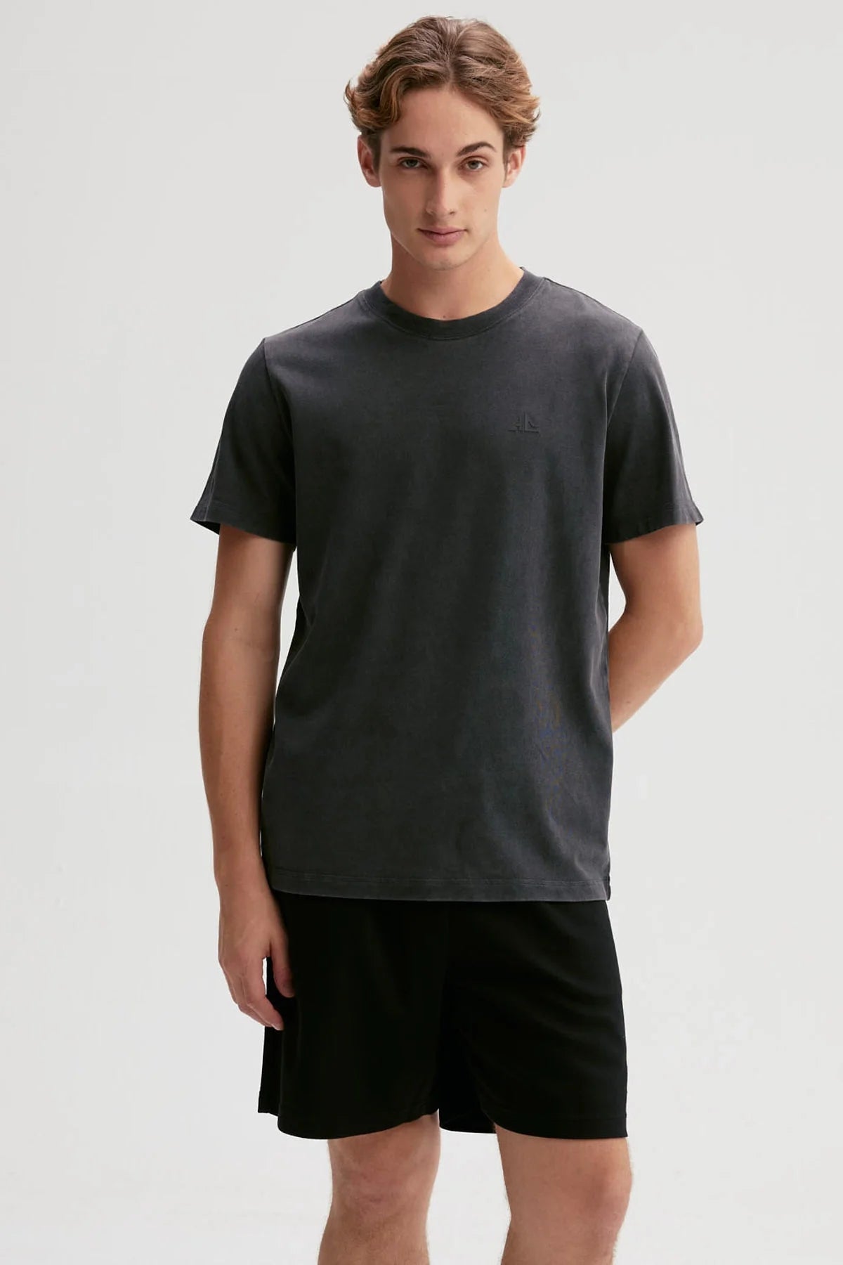 Polera negra de algodón 100% con diseño minimalista de logo en el pecho, ideal para los fanáticos de la moda urbana y el estilo casual.