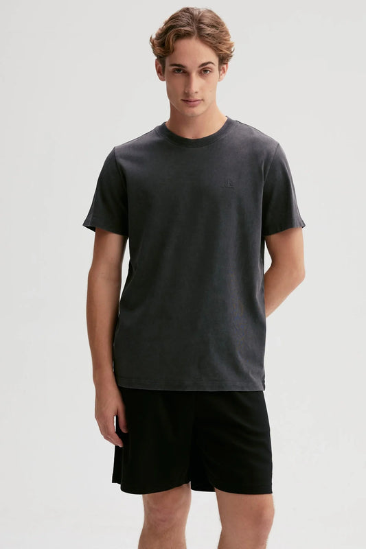 Polera negra de algodón 100% con diseño minimalista de logo en el pecho, ideal para los fanáticos de la moda urbana y el estilo casual.