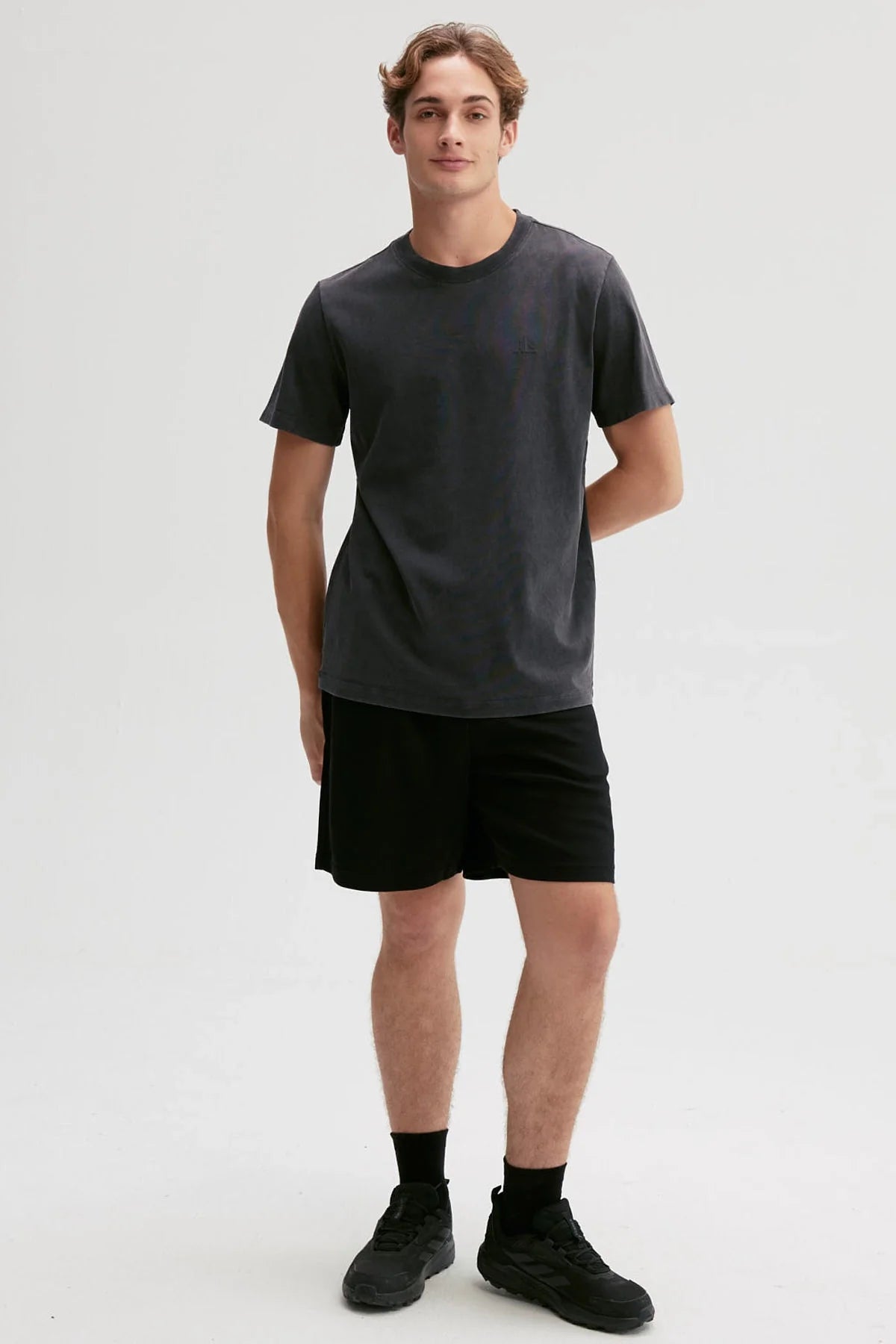 Polera negra de algodón 100% con diseño minimalista de logo en el pecho, ideal para los fanáticos de la moda urbana y el estilo casual.