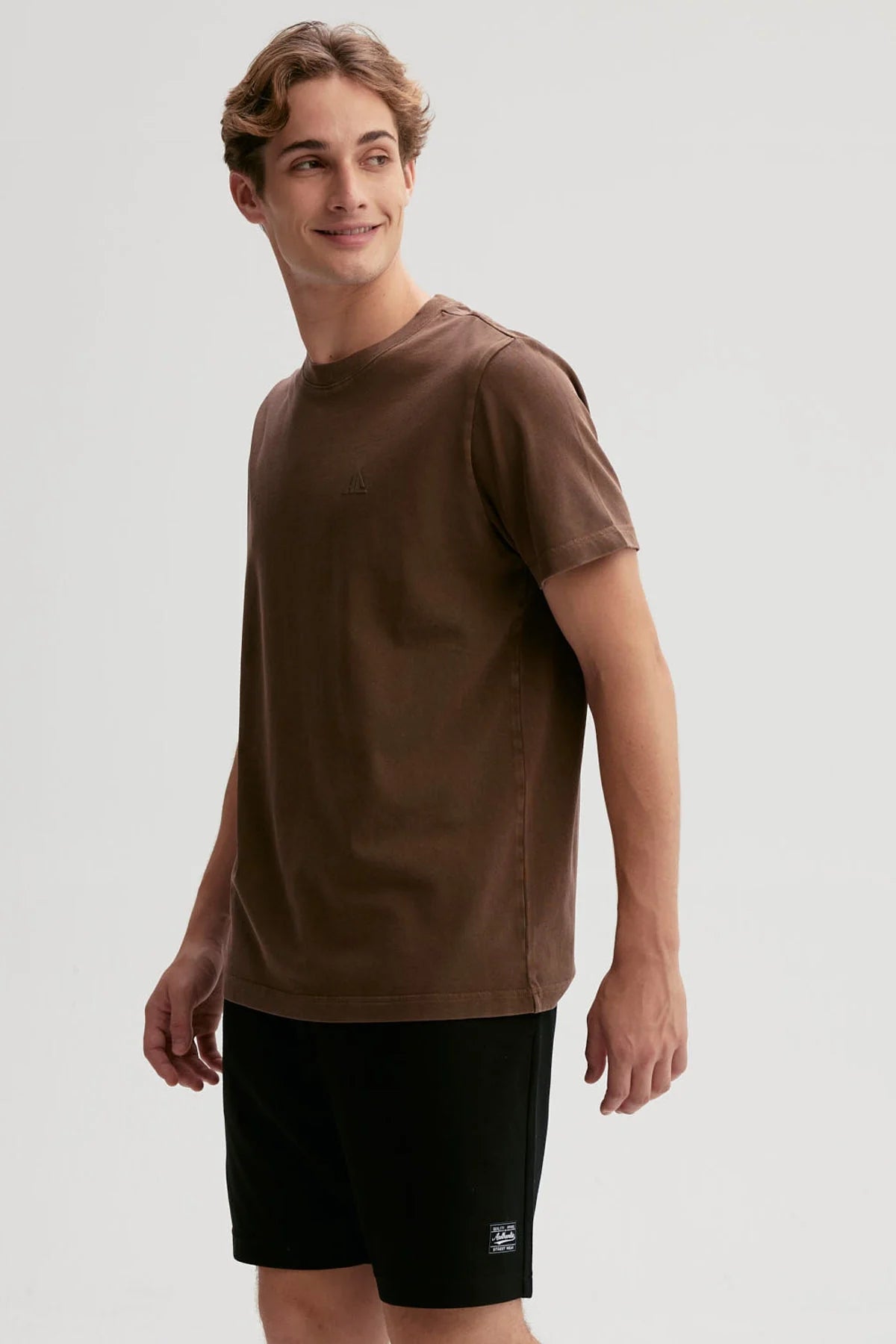 Polera de algodón marrón con un sutil logo en relieve, ideal para los fanáticos del café y la cultura pop, perfecta para mostrar tu estilo único.