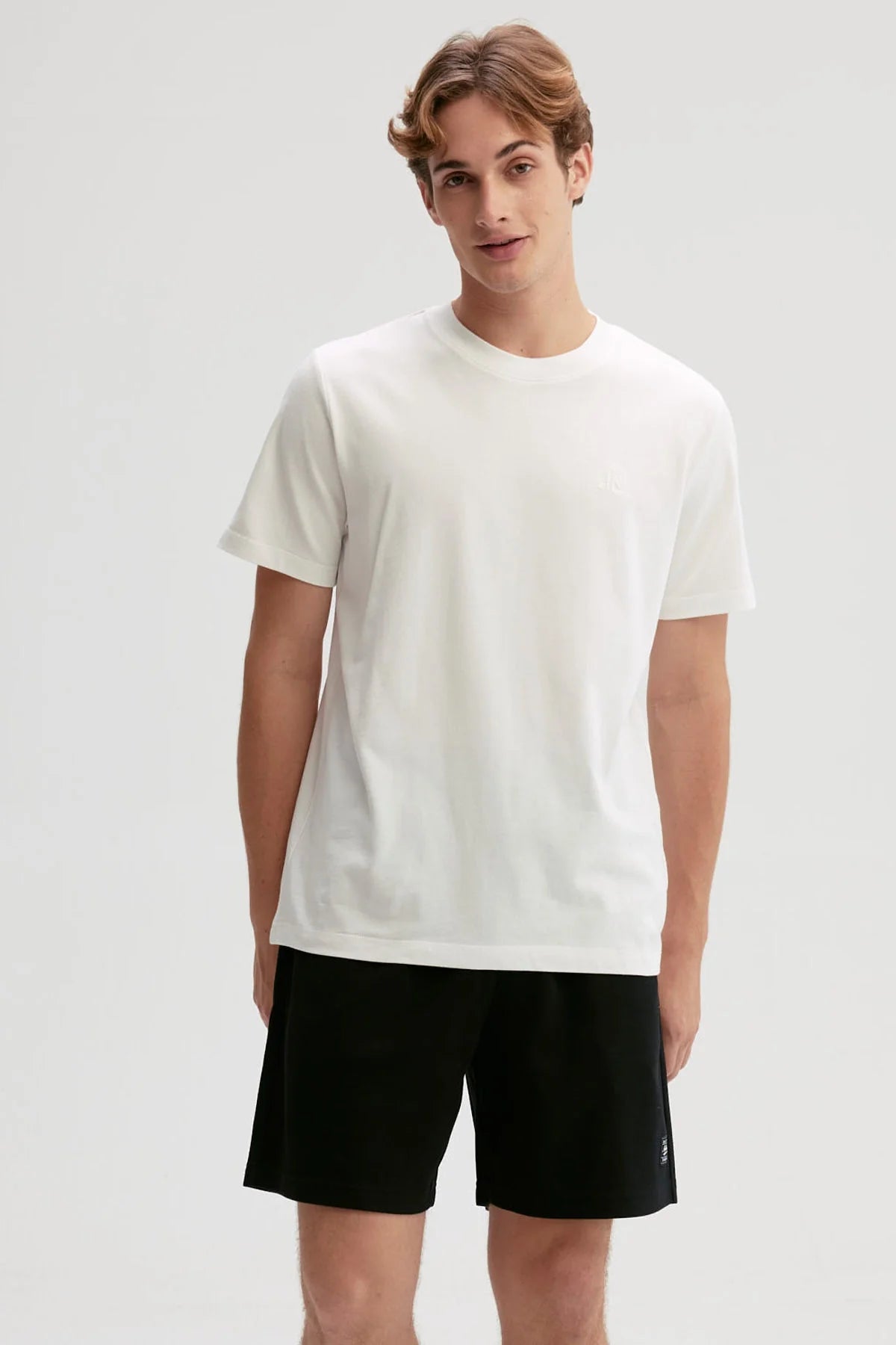 Polera blanca de algodón con diseño minimalista, presenta un logo sutil en el pecho, ideal para fans de la moda casual y contemporánea.