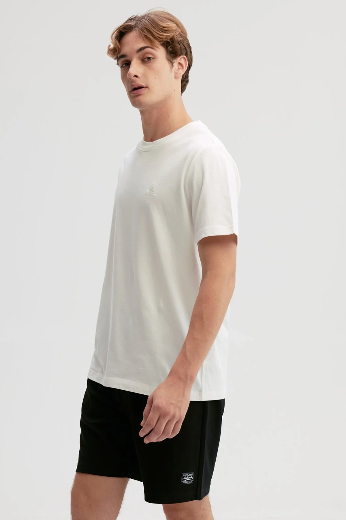 Polera blanca de algodón con diseño minimalista, presenta un logo sutil en el pecho, ideal para fans de la moda casual y contemporánea.