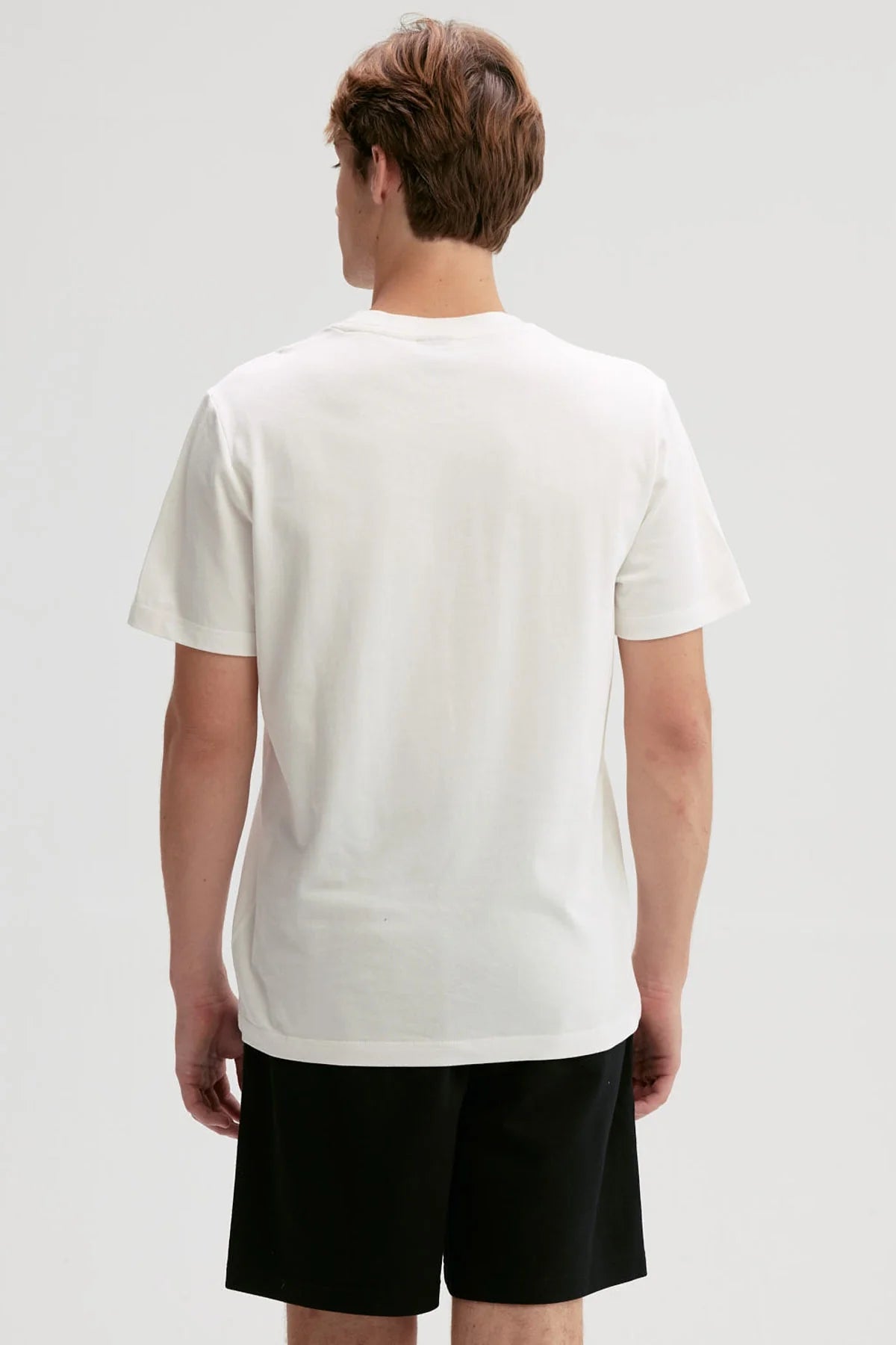 Polera blanca de algodón con diseño minimalista, presenta un logo sutil en el pecho, ideal para fans de la moda casual y contemporánea.