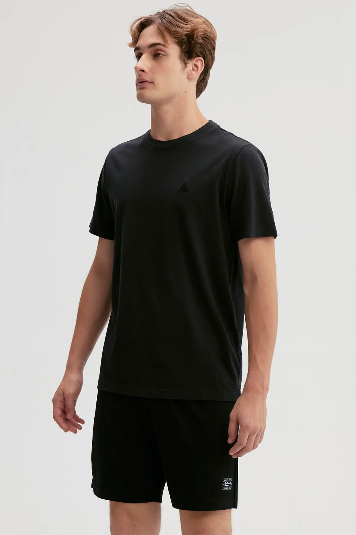 Polera negra de algodón con un diseño minimalista que presenta un logo sutil en el pecho, ideal para los fans de la moda urbana y el estilo casual.