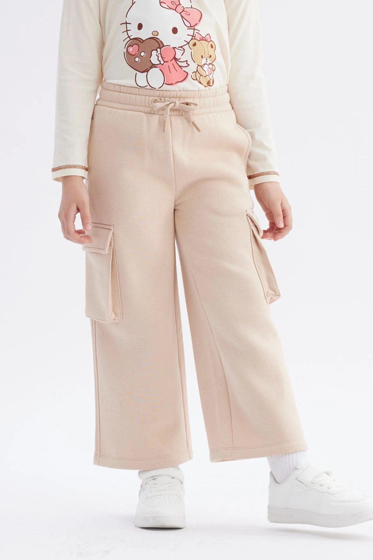 Pantalón buzo beige de corte amplio con bolsillos laterales, ideal para un look casual y cómodo, perfecto para los fans de la cultura pop.